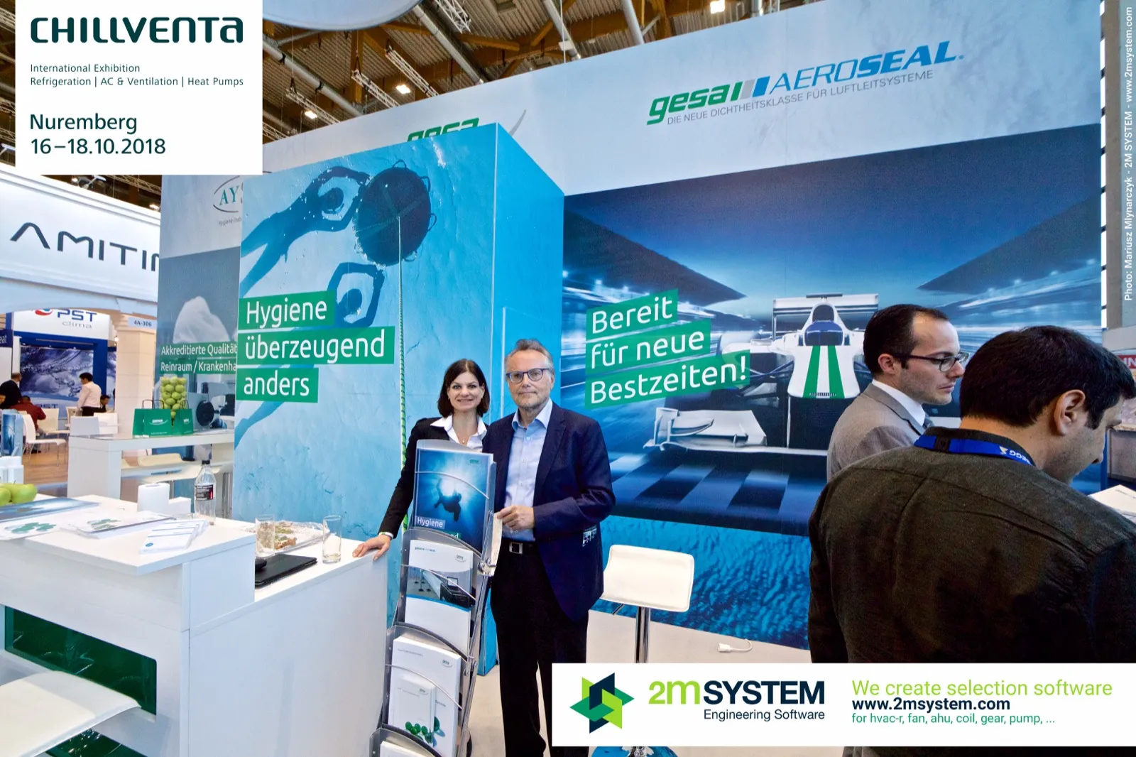 Exhibitors posing with brochures before the gesa Aeroseal race car graphic at Chillventa 2018
