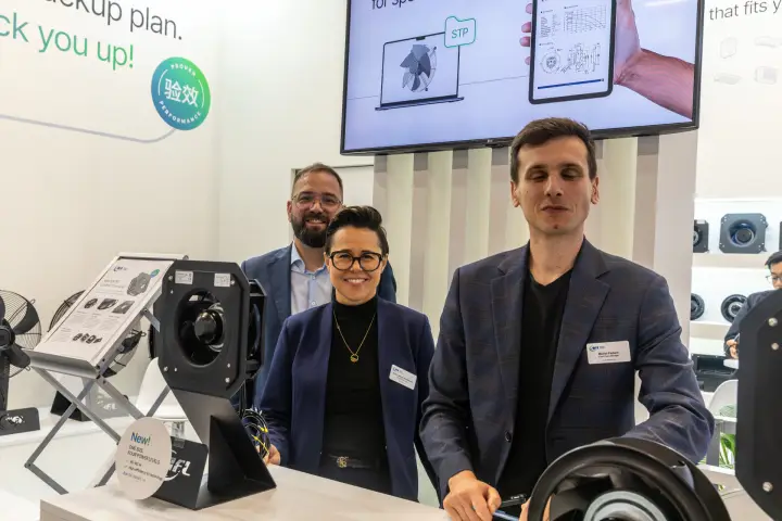 AFL Motors Europe team behind compact EC fans and a "New!" sign