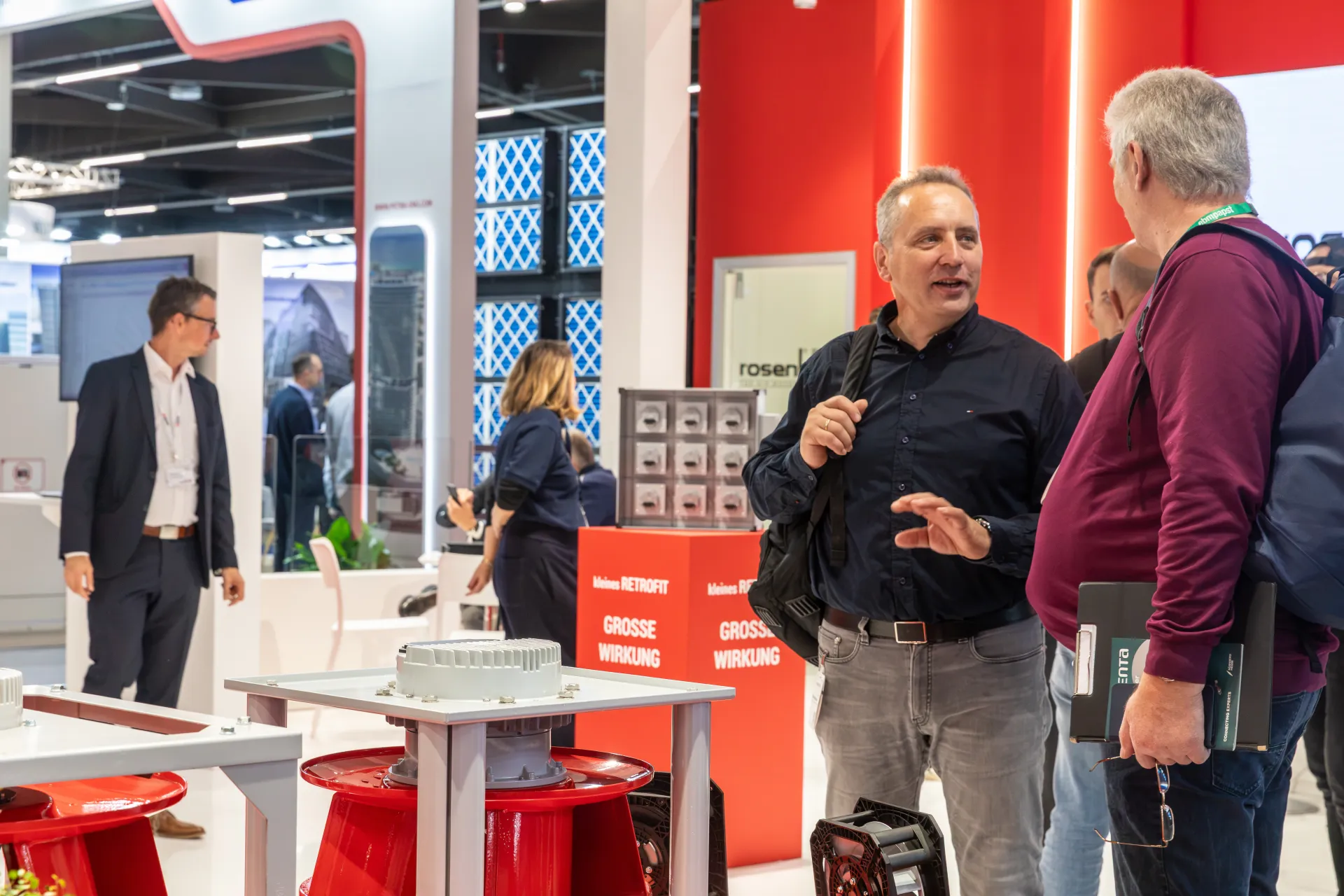 Conversation at Rosenberg beside red fan impellers and a retrofit display at Chillventa 2026