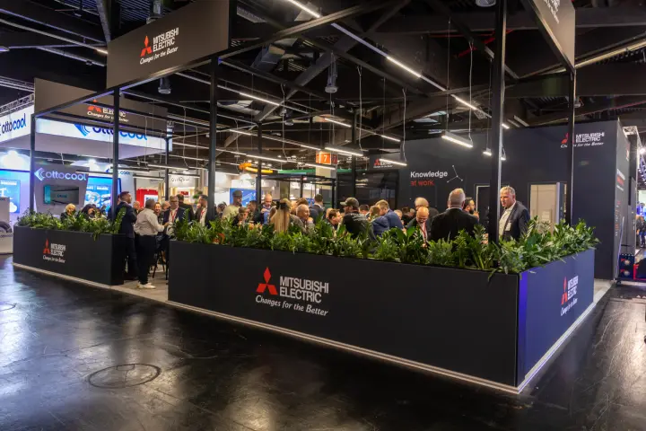 Crowded Mitsubishi Electric hospitality area framed by black planters
