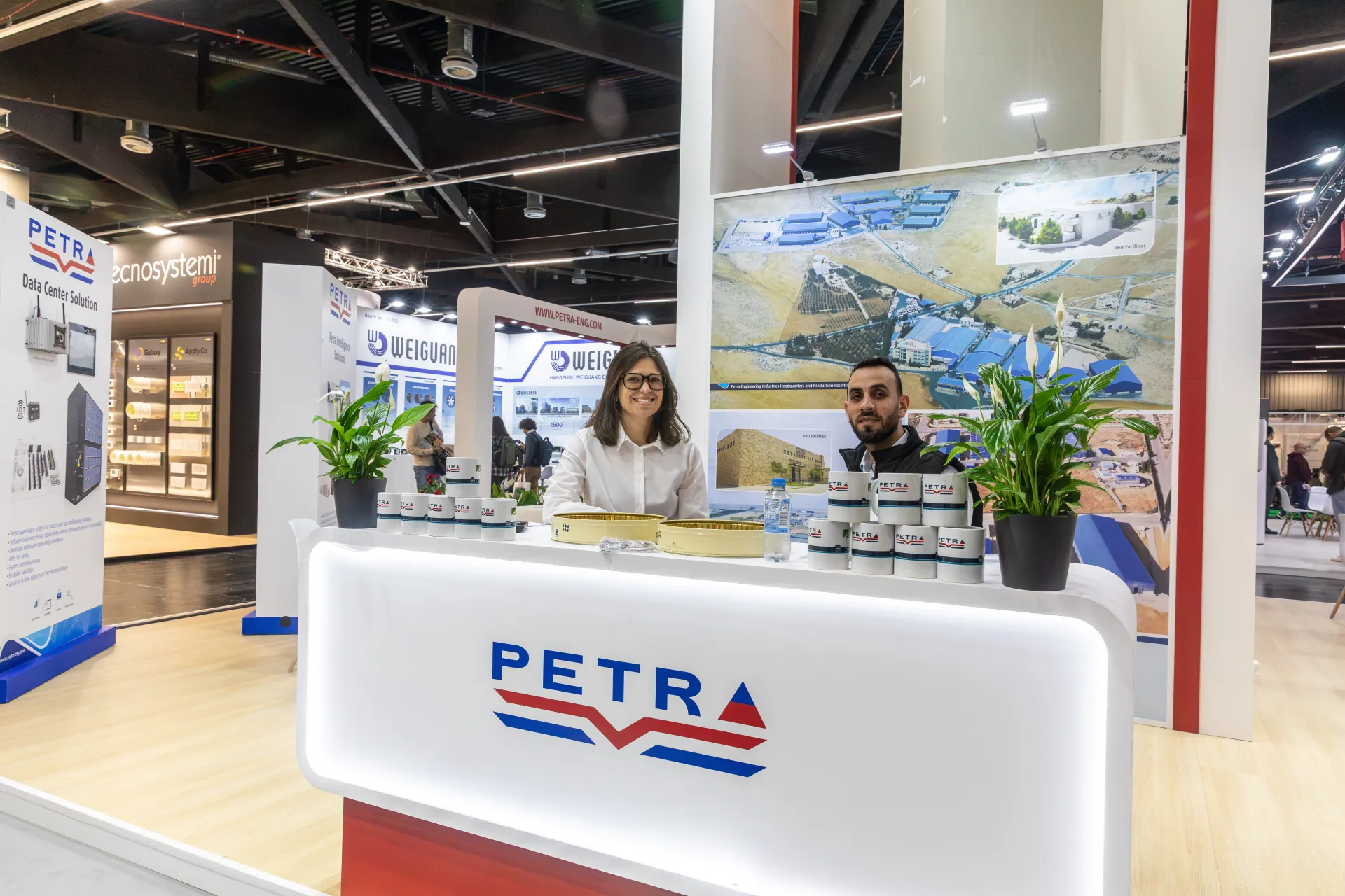 Petra reception counter with branded mugs and a factory aerial photo at Chillventa 2026