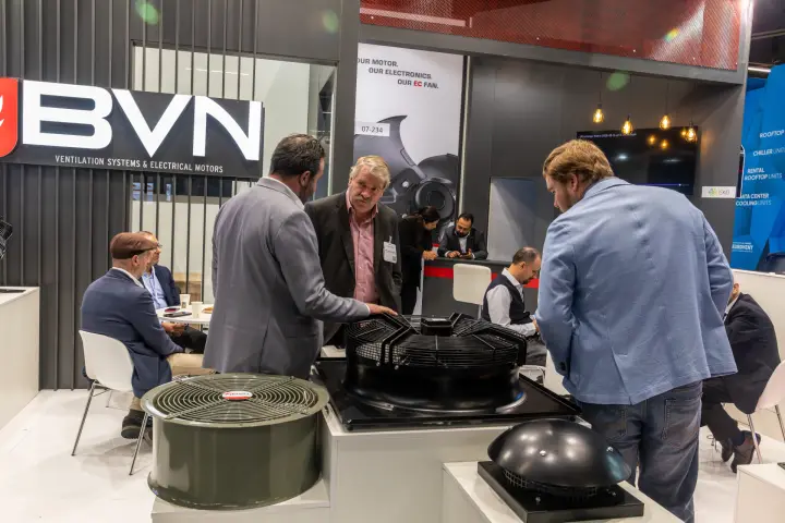 Visitors discussing a large axial fan with guard at the BVN stand