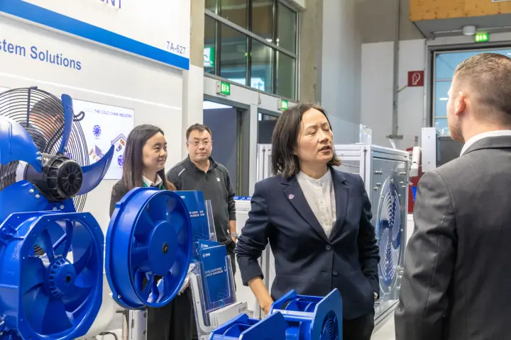 Xiangming Intelligent staff talking with a visitor beside blue axial fans at Chillventa 2026