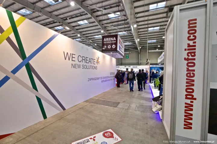 Mitsubishi Electric "We Create New Solutions" wall along an aisle