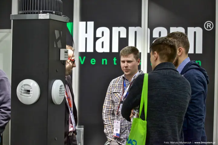 Visitors talk beside a Harmann display column in front of the logo wall at Forum Wentylacja 2016