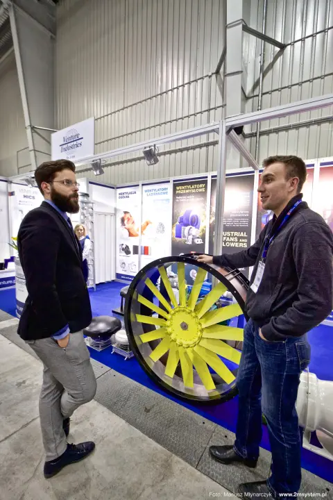 Visitors talking beside a yellow-bladed axial fan at Venture Industries at Forum Wentylacja 2016
