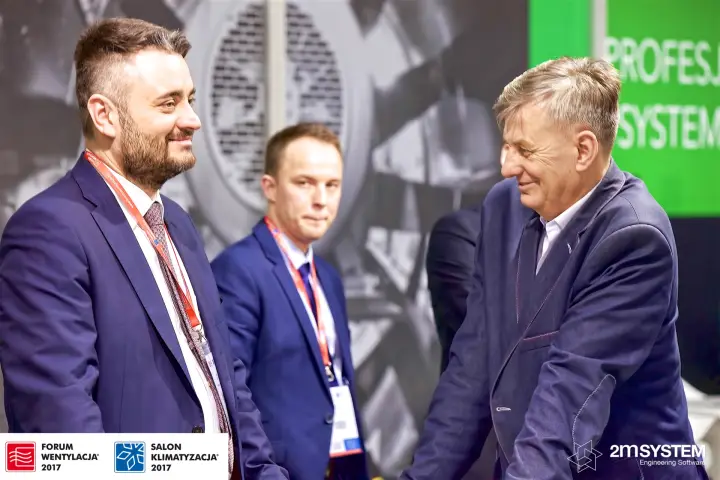 Conversation at the Harmann stand in front of a large fan graphic at Forum Wentylacja 2017