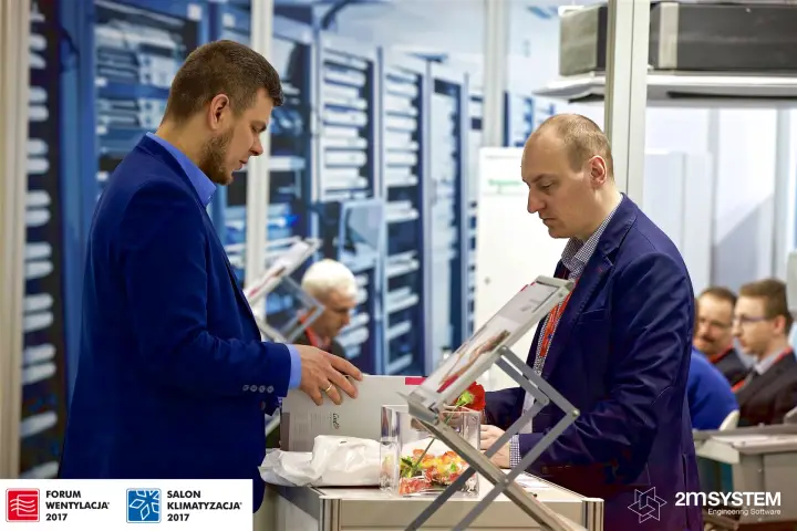 Conversation over a catalogue in front of a server-room wall graphic at Forum Wentylacja 2017