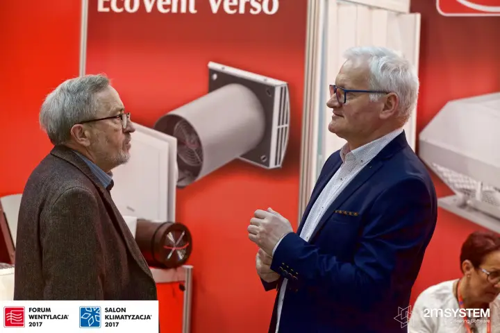 Discussion in front of the EcoVent Verso graphic on a red Helios wall at Forum Wentylacja 2017