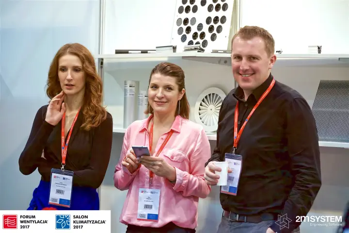 Exhibitors in front of a shelf of swirl diffusers and grilles