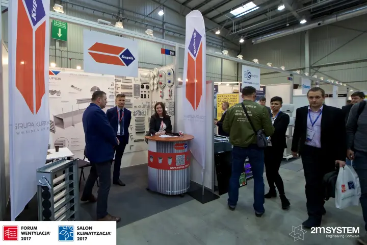 Kupsik stand with a wall of duct fittings and orange feather flags