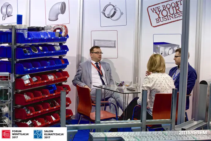 Meeting table beside duct accessory bins and a We Boost Your Business wall