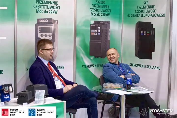 Stand with frequency inverter banners and a seated meeting