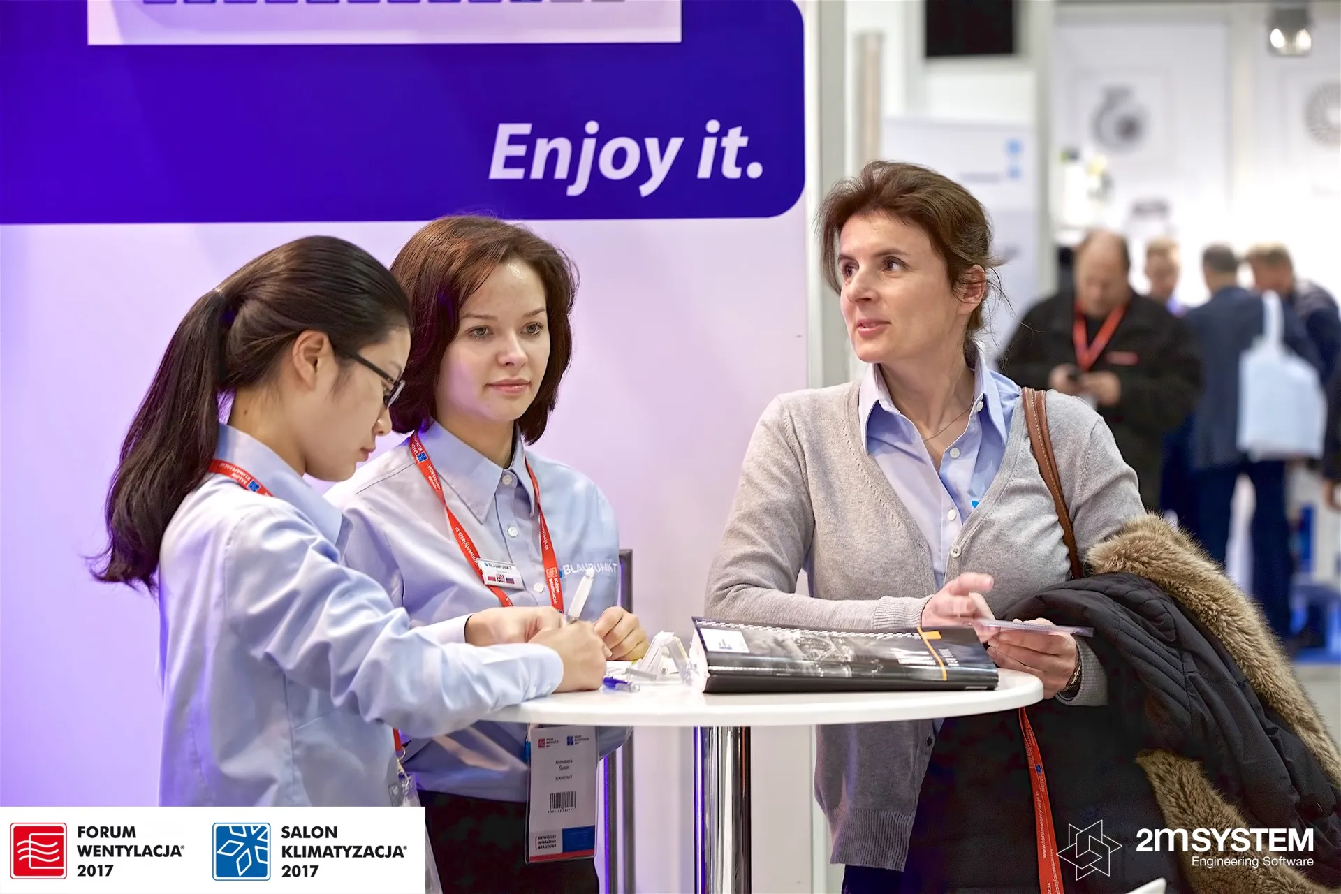 Visitor talking to Blaupunkt staff under the "Enjoy it." slogan at Forum Wentylacja 2017