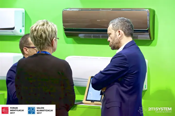 Visitors before AUX wall units on a lime green display wall at Forum Wentylacja 2017