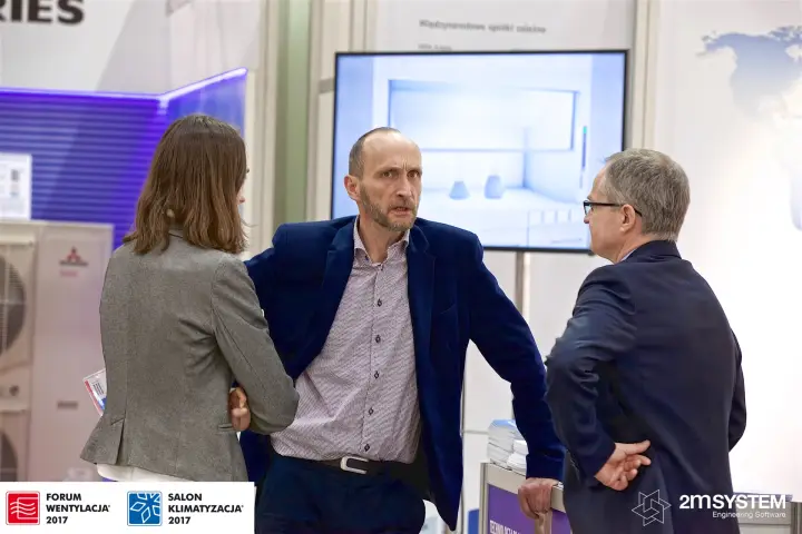 Visitors in conversation in front of a display screen at a stand