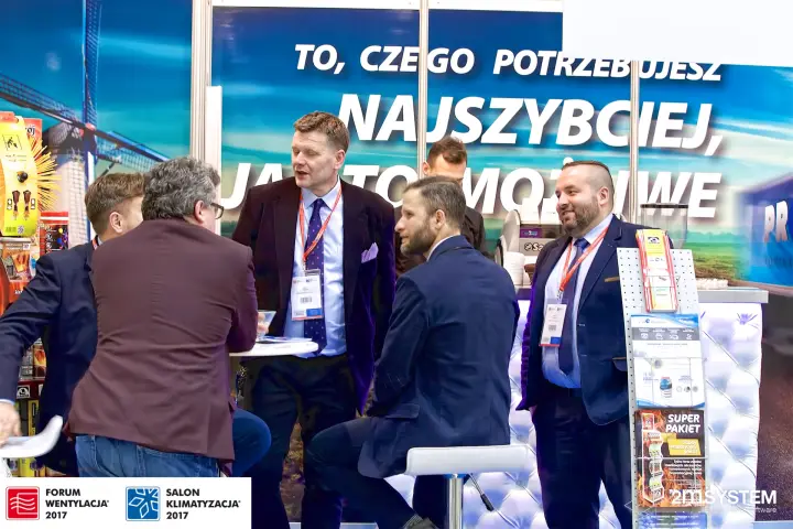 Visitors in conversation under a large Polish slogan graphic