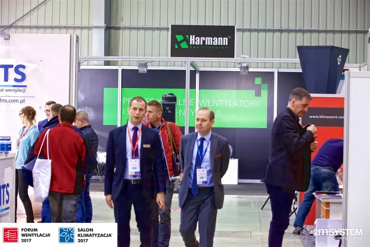 Visitors pass the Harmann stand sign in the aisle beside HTS at Forum Wentylacja 2017