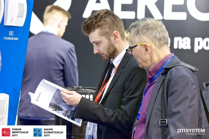 Visitors reading an Aereco catalogue beside the BXC exhaust unit display at Forum Wentylacja 2017