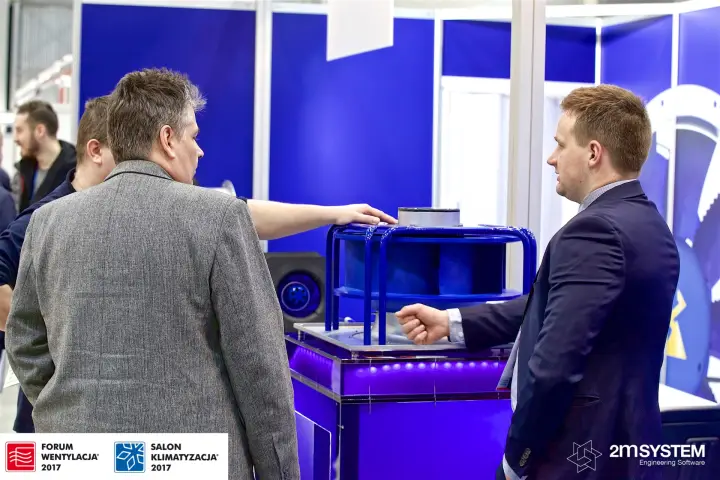Ziehl-Abegg staff explaining a plug fan impeller on an illuminated plinth at Forum Wentylacja 2017
