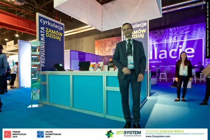 Full-length portrait beside the turquoise Cyrkulacje counter
