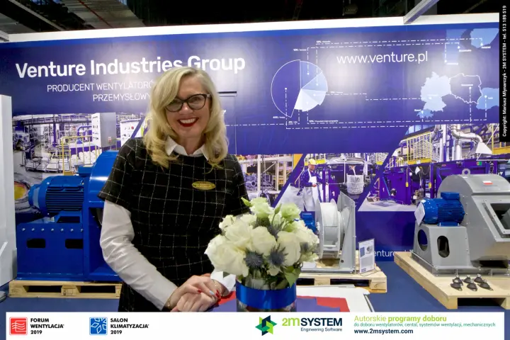 Portrait at Venture Industries counter with blue motor-driven centrifugal fan at Forum Wentylacja 2019
