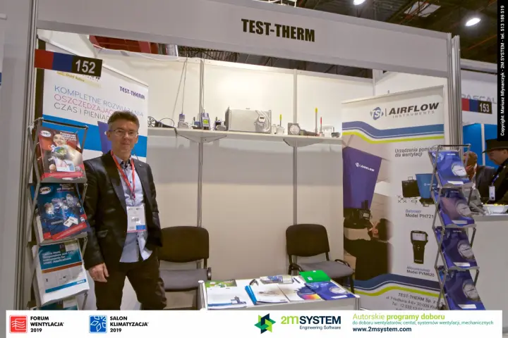 Staff portrait at Test-Therm stand beside brochure racks and TSI banner at Forum Wentylacja 2019