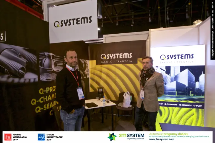 Staff at the Q Systems booth with its yellow corrugated-pipe backdrop