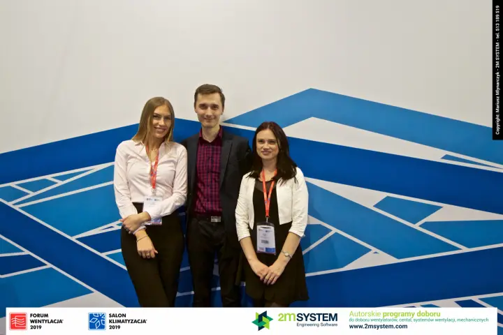Three Aereco stand staff against the blue geometric wall graphic at Forum Wentylacja 2019