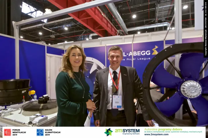 Two people at Ziehl-Abegg beside a large blue-bladed axial fan