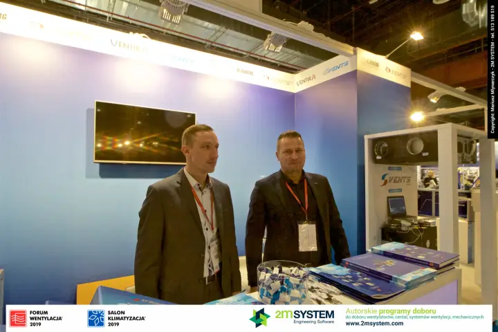 Vents staff by the blue wall with brand fascia and a framed heat recovery unit at Forum Wentylacja 2019