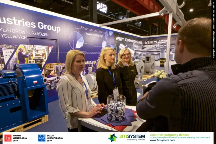 Venture Industries staff at the counter beside a blue centrifugal fan at Forum Wentylacja 2019