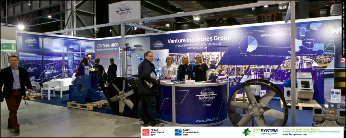 Venture Industries staff and a visitor pose at the round branded counter at Forum Wentylacja 2019