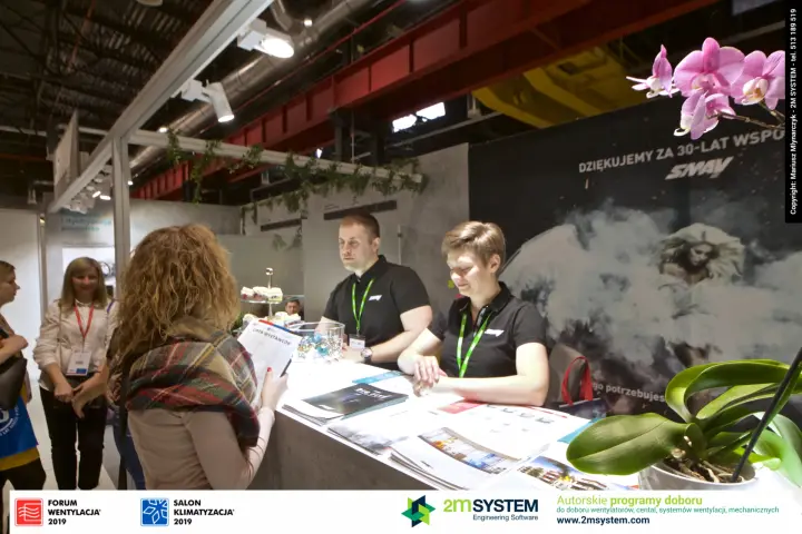 Visitors consulting staff at the SMAY reception desk with catalogues at Forum Wentylacja 2019