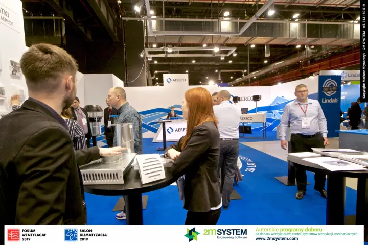 Visitors handling Aereco vents and grilles at a high table at Forum Wentylacja 2019