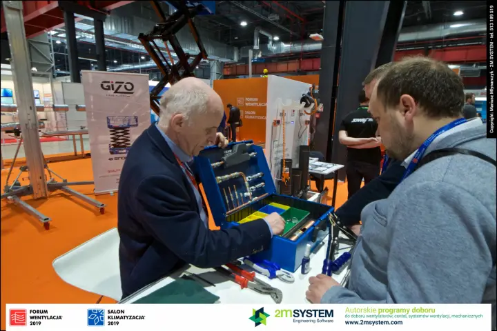 Visitors inspect a blue installer tool case with copper fittings