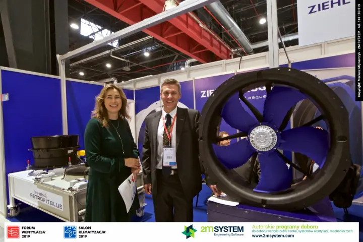 Ziehl-Abegg staff beside a large axial fan and RETROFITBLUE display