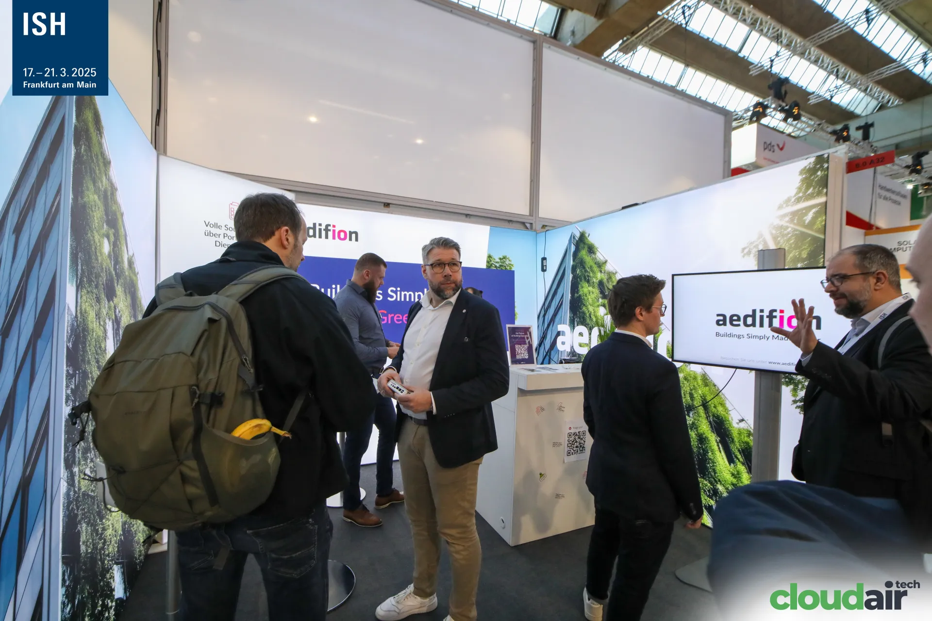 Aedifion stand with backlit green facade panels and logo screen at ISH 2025