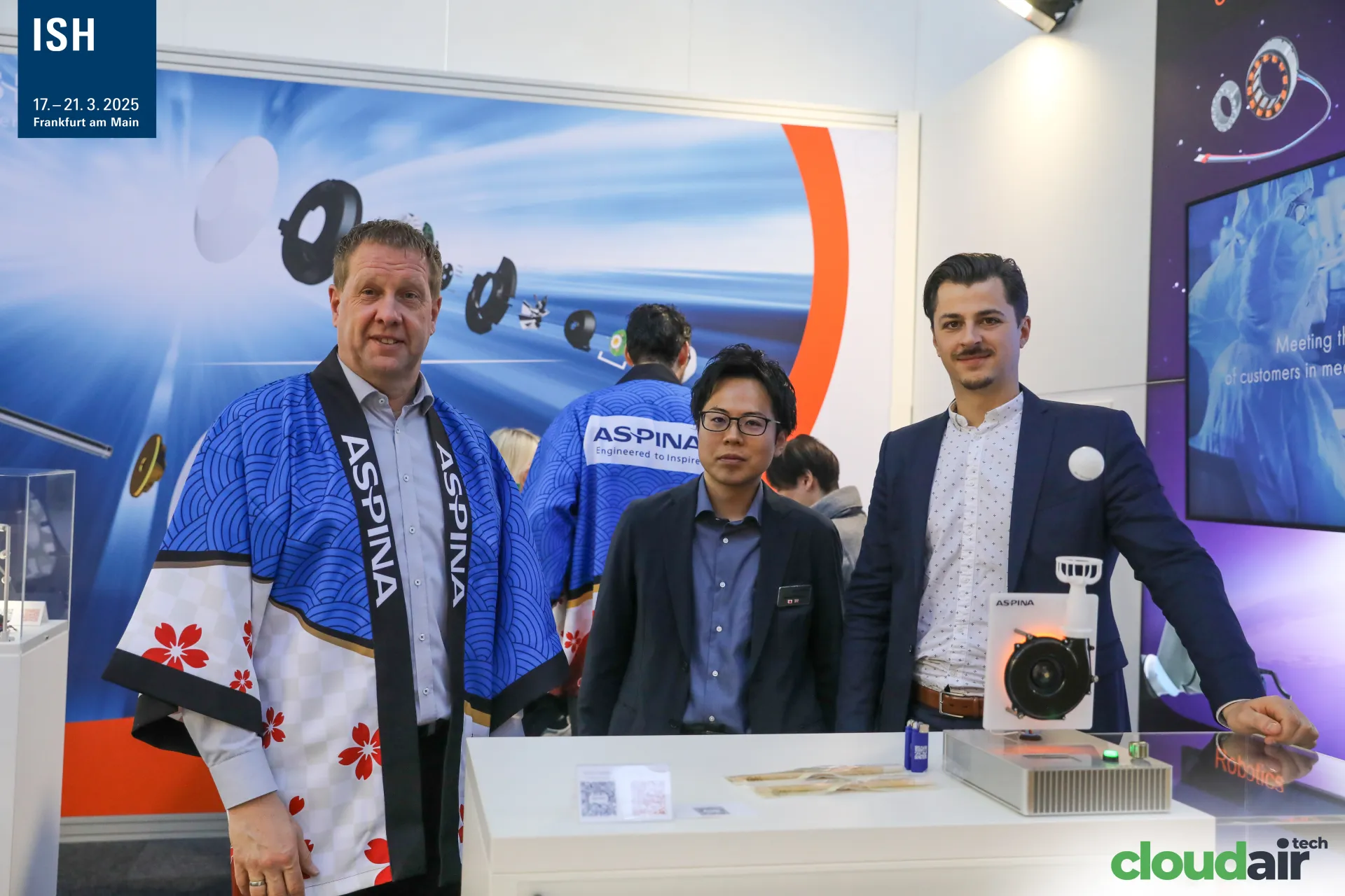 Aspina team in branded happi coats at a lit blower display at ISH 2025