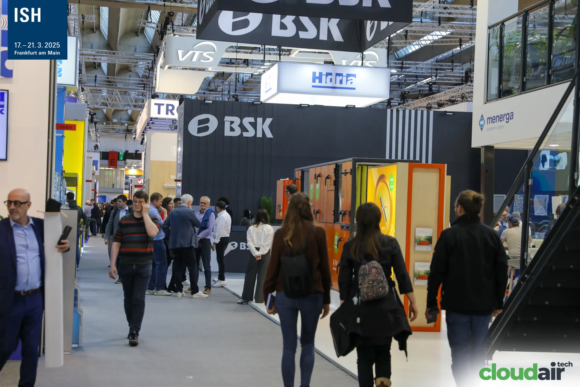 Busy aisle between the dark BSK stand and an orange Menerga unit at ISH 2025