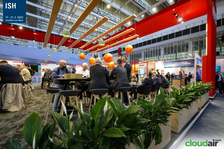 Busy stand lounge with orange globe lamps and wooden ceiling beams at ISH 2025