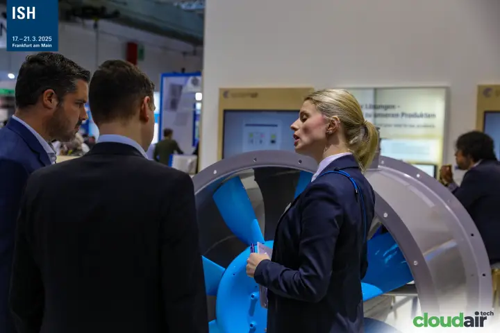 Close discussion in front of a light-blue bladed axial fan at Systemair