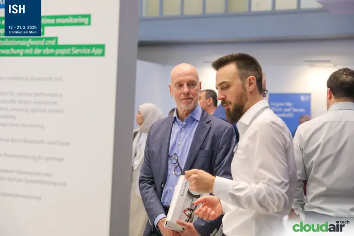 Conversation beside an ebm-papst Service App information panel at ISH 2025
