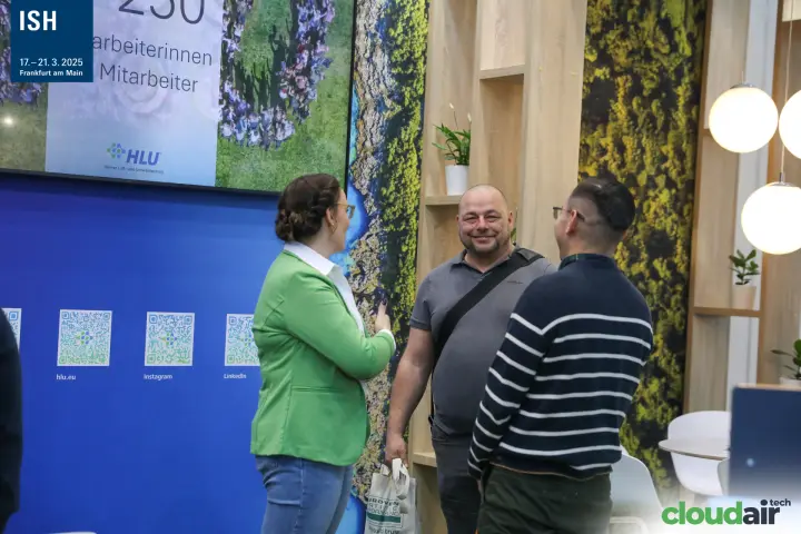 Conversation at the HLU stand beside QR codes and an employee screen at ISH 2025