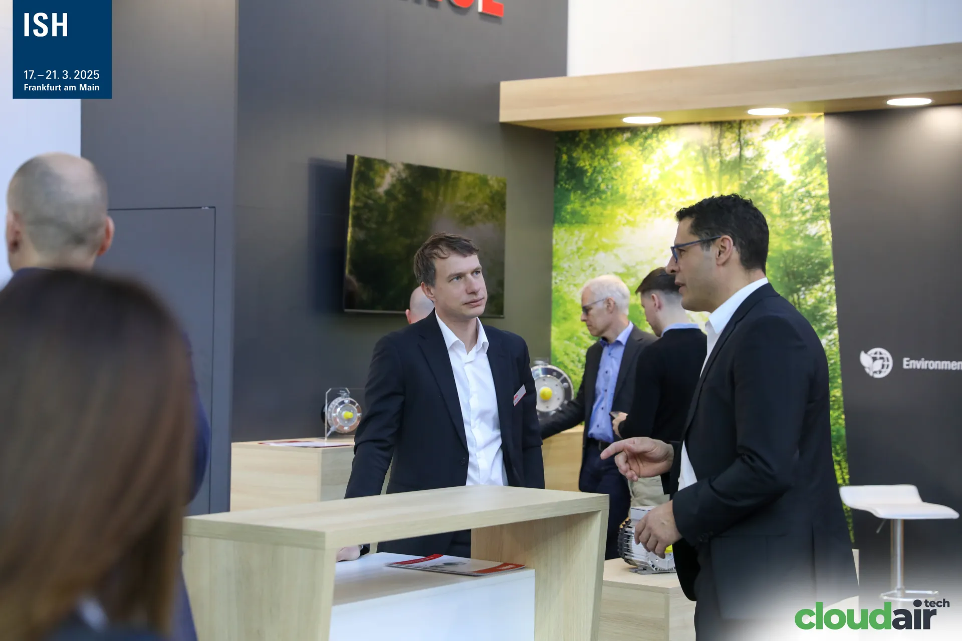 Conversation at a light-wood counter on the Domel stand at ISH 2025