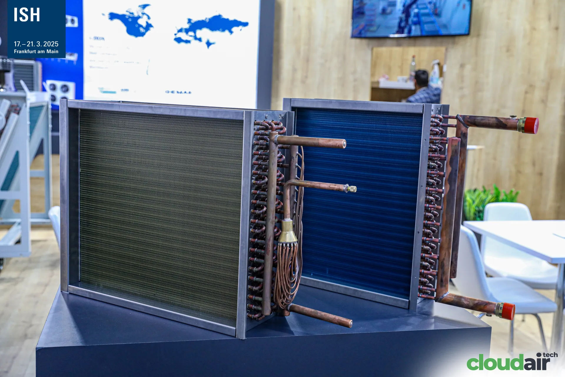 Copper-tube finned coils with distributor on a dark display plinth at ISH 2025