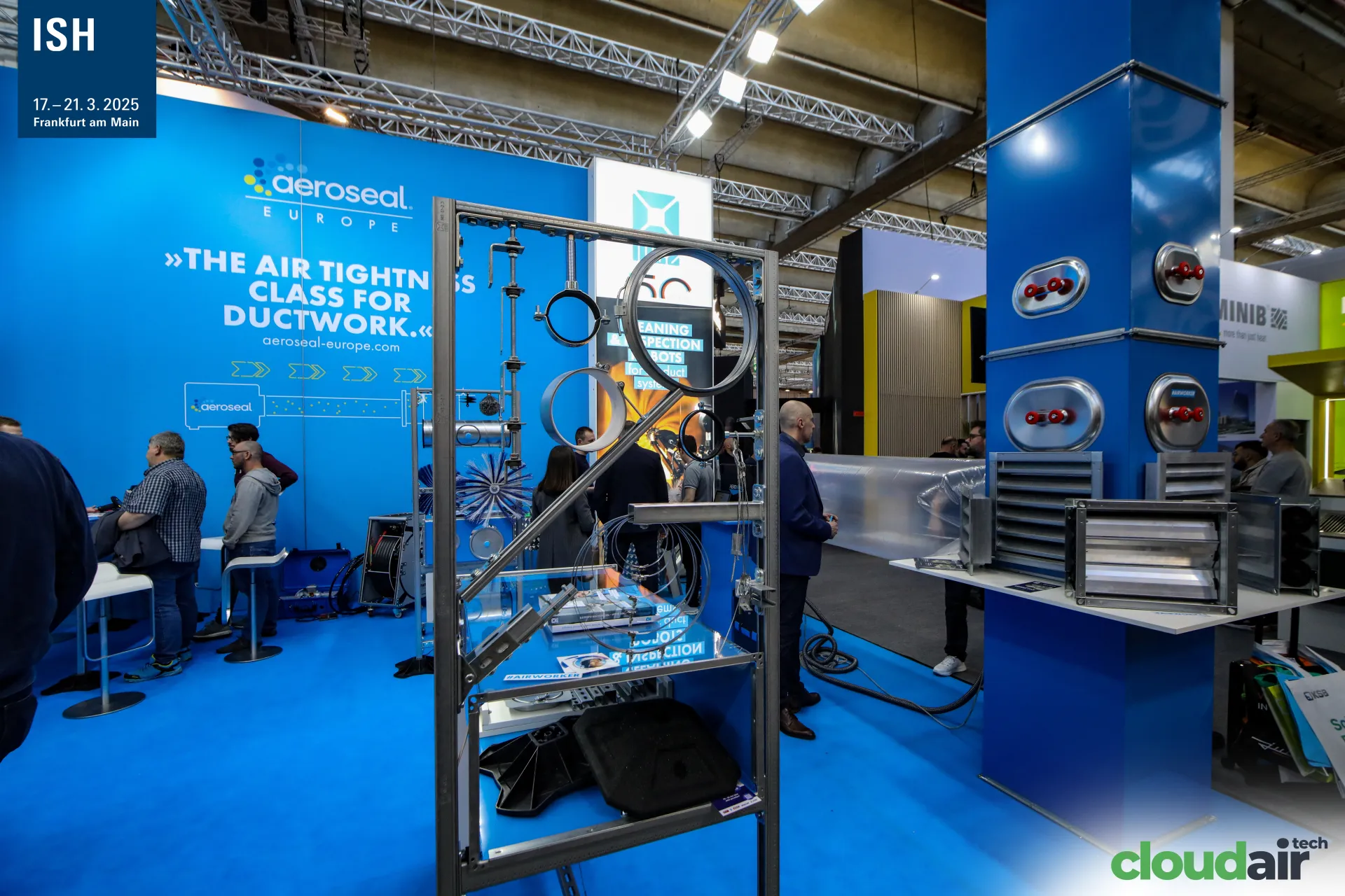 Duct hangers, cleaning brushes and dampers in front of the Aeroseal wall at ISH 2025