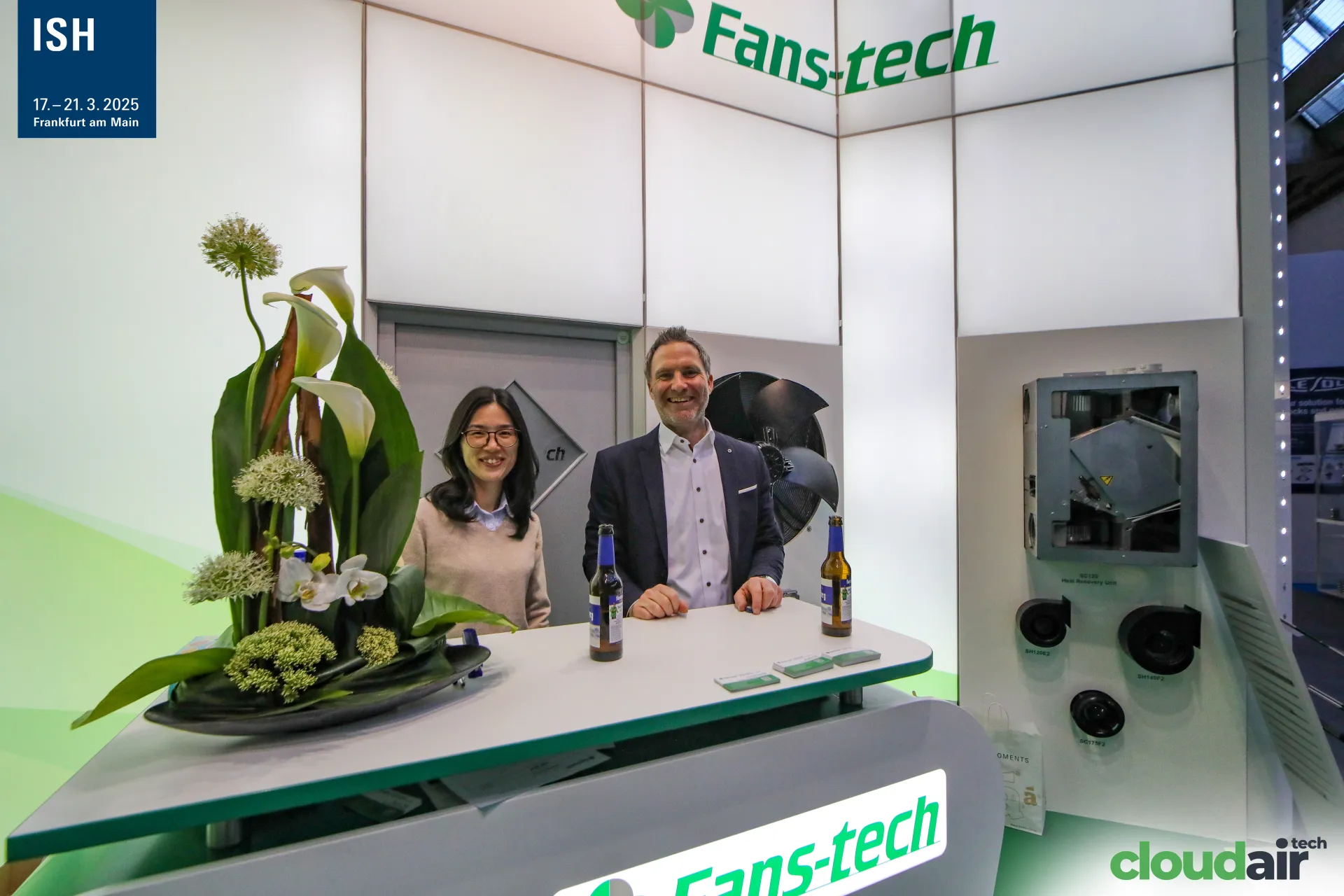 Fans-tech staff at the counter beside a heat recovery unit display at ISH 2025