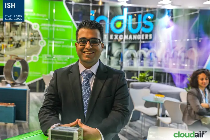 Indus staff member holding a compact finned coil heat exchanger at ISH 2025