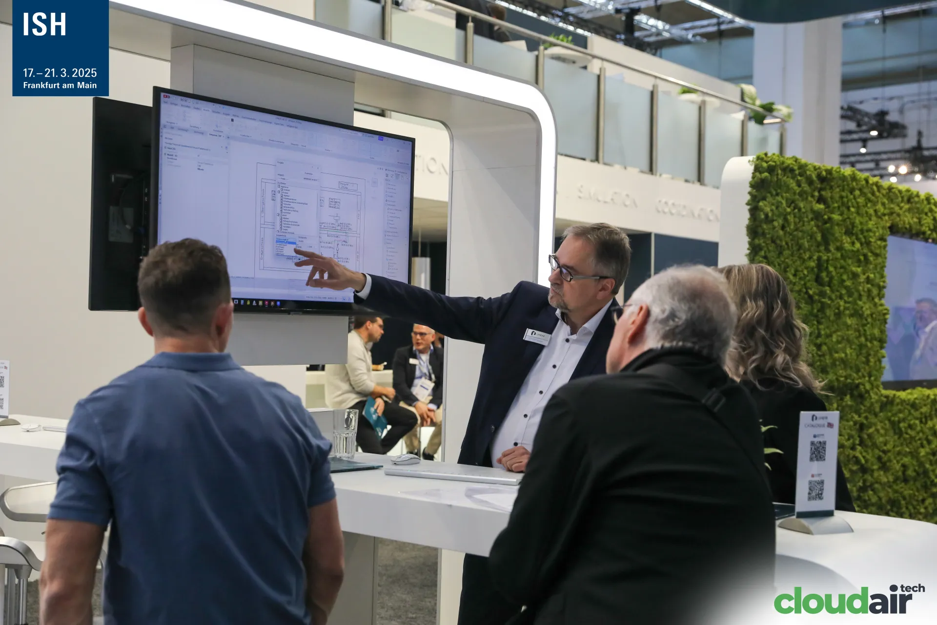 Linear staff explaining a CAD floor plan to visitors at ISH 2025